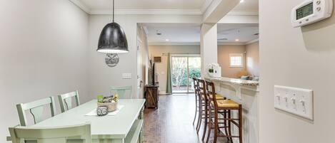 A dining area with a long table, chairs, and a hanging light fixture.