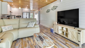 A modern living room with a sofa, a coffee table, a TV, and a wooden cabinet. - Near Beaches: Waterfront Gem in Anna Maria Island! (Holmes Beach)