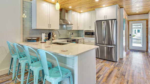 A modern kitchen with white cabinets, a stainless steel refrigerator, and a wooden ceiling. - Near Beaches: Waterfront Gem in Anna Maria Island! (Holmes Beach)