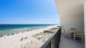 Un balcon donnant sur une plage, une terrasse en bois et une table avec des chaises.