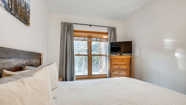 A bedroom with a bed, a TV on a wooden dresser, and a window with curtains. - Walk to Ski Lift & Hot Tubs! Mtn-view Keystone Gem (Keystone)