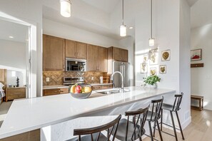 A modern kitchen with a large island, bar stools, wooden cabinets, stainless steel appliances, and pendant lighting. - 5 Mi to Winter Park Resort! Hot Tub Haven w/ Views (Winter Park)