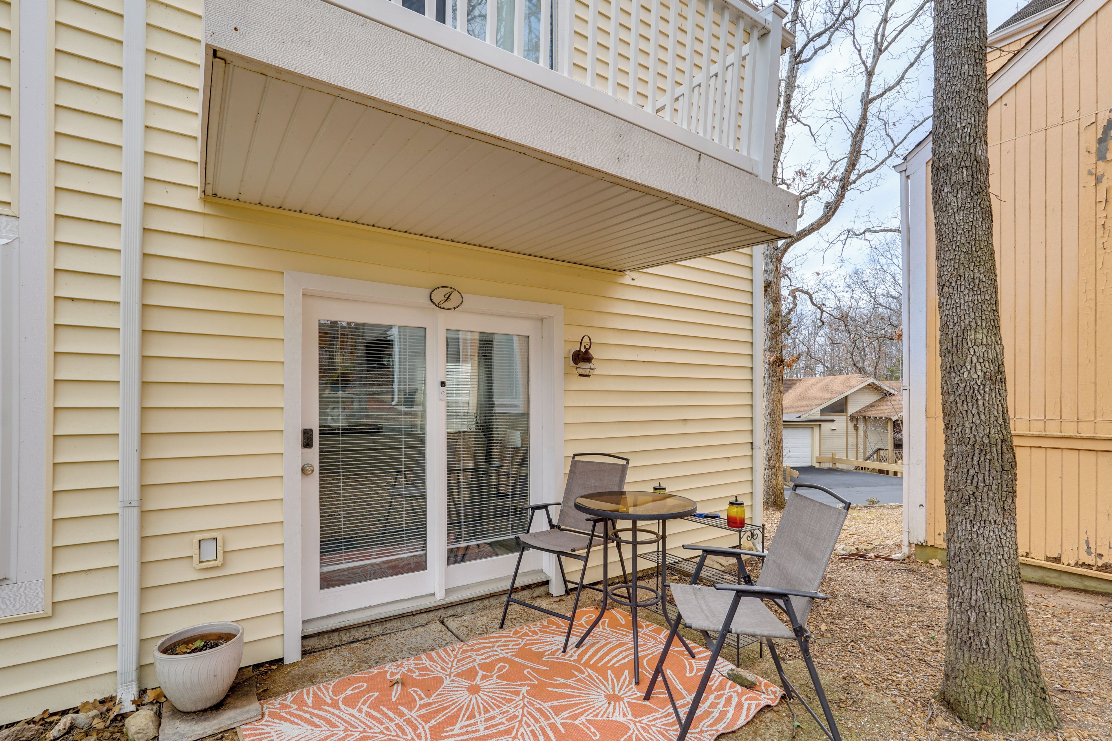 Eine überdachte Terrasse mit Tisch und Stühlen, einem Blumentopf und einer Tür mit Fenster.