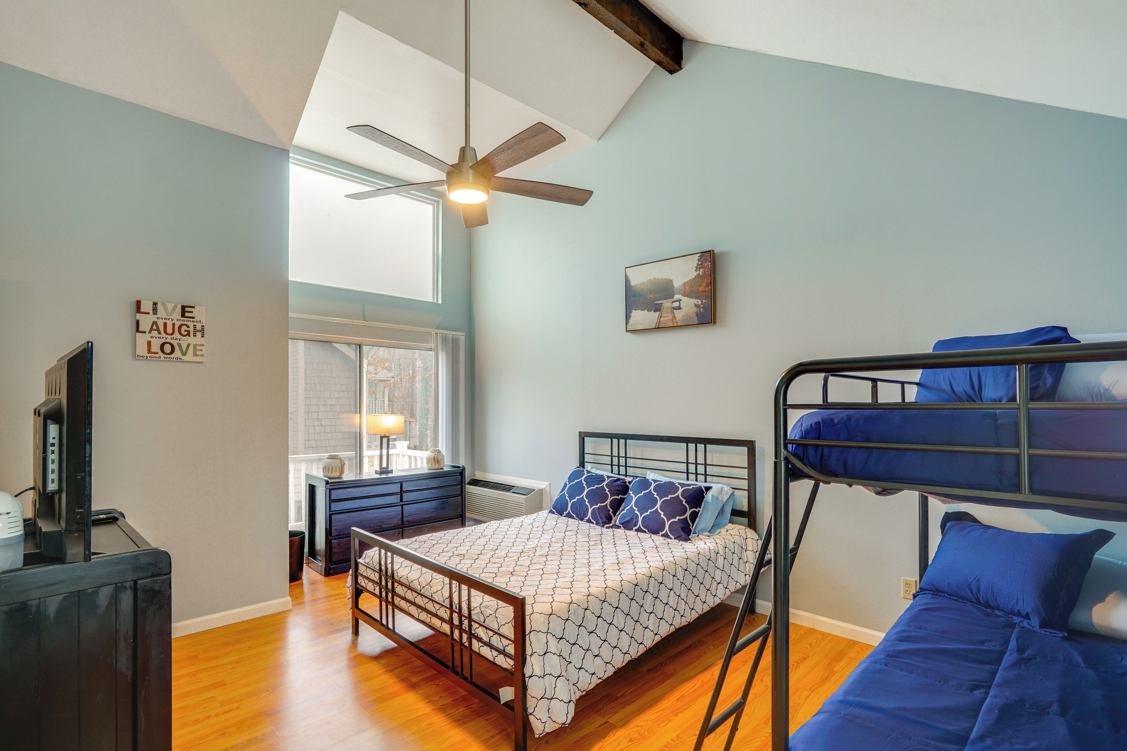 A bedroom with a bunk bed, a desk, and a ceiling fan.