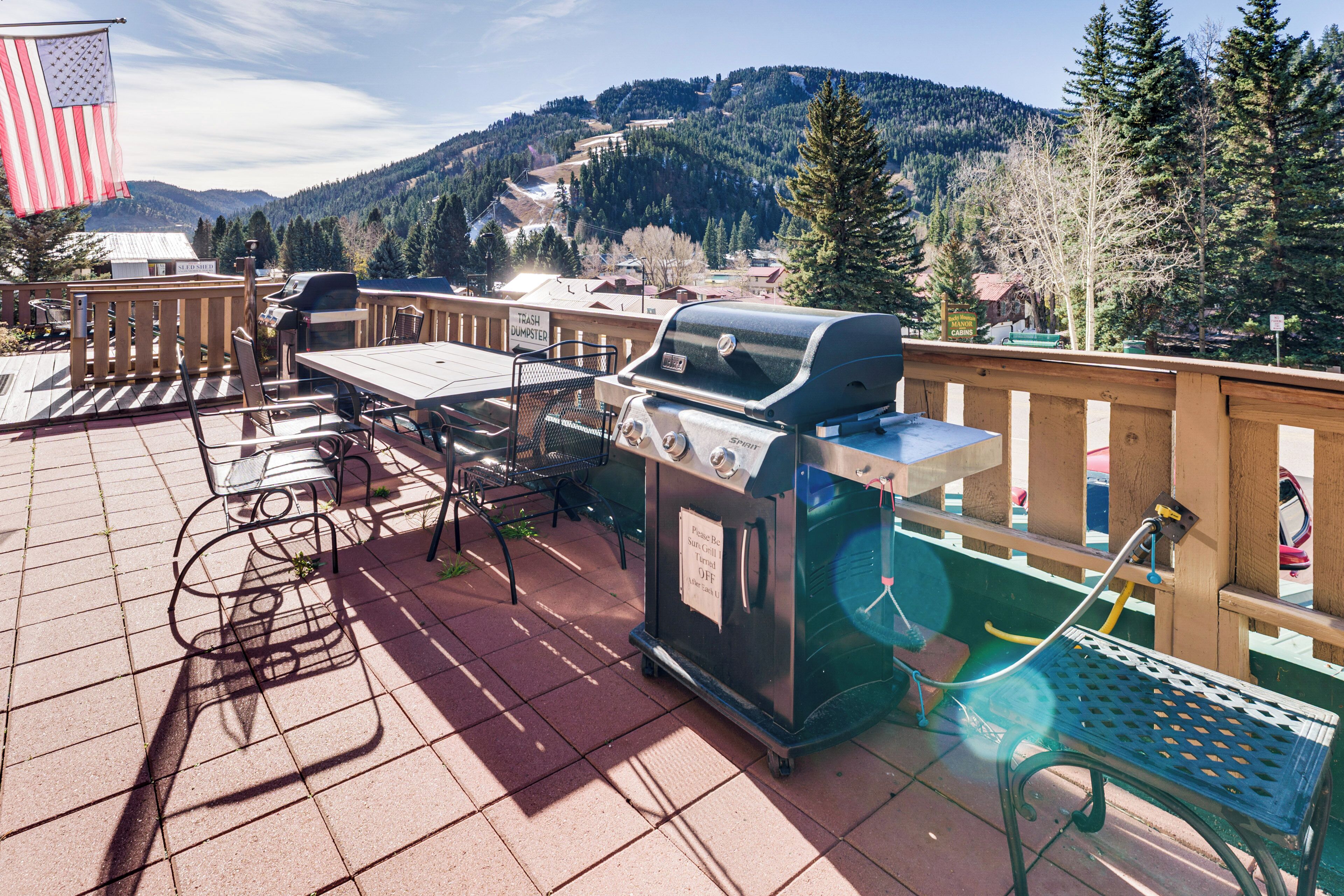 Une terrasse extérieure équipée d’un barbecue, de sièges et offrant une vue sur les montagnes.