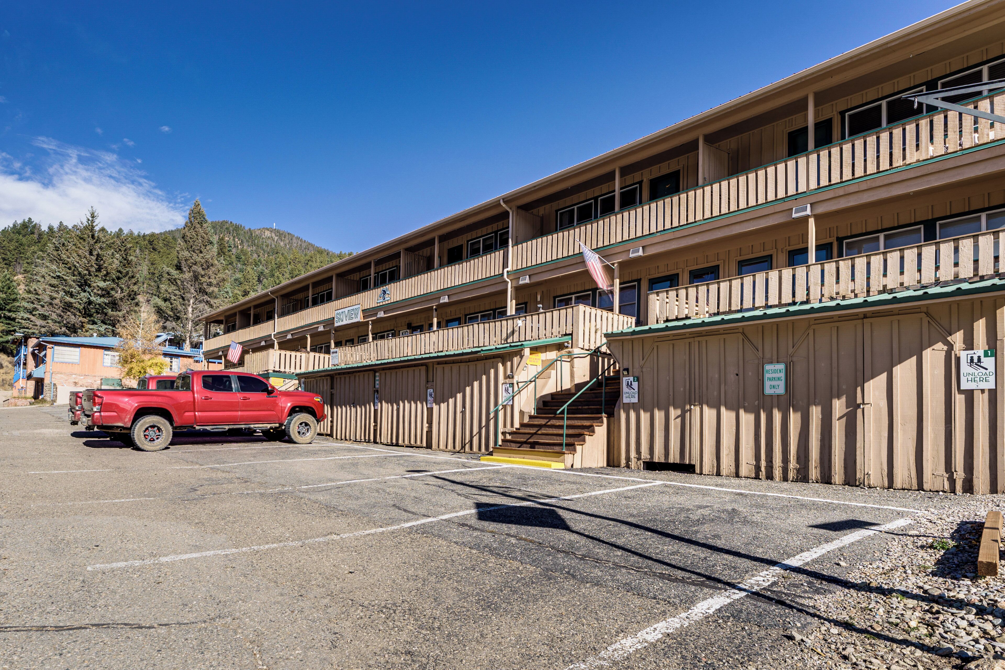A multi-story building with a parking lot, a red truck, and a staircase leading to an upper level.