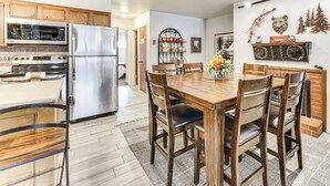 Eine moderne Küche mit Edelstahlgeräten, Holzschränken und einem Essbereich mit Holztisch und Stühlen.