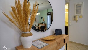 A wooden console table with a vase of golden grasses, a round mirror, and a framed certificate. - Thyme Out - Modern Apartment in Egaleo/Athens (Egaleo)