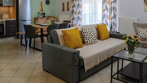 A modern living room with a sofa, coffee table, and dining area. - Thyme Out - Modern Apartment in Egaleo/Athens (Egaleo)