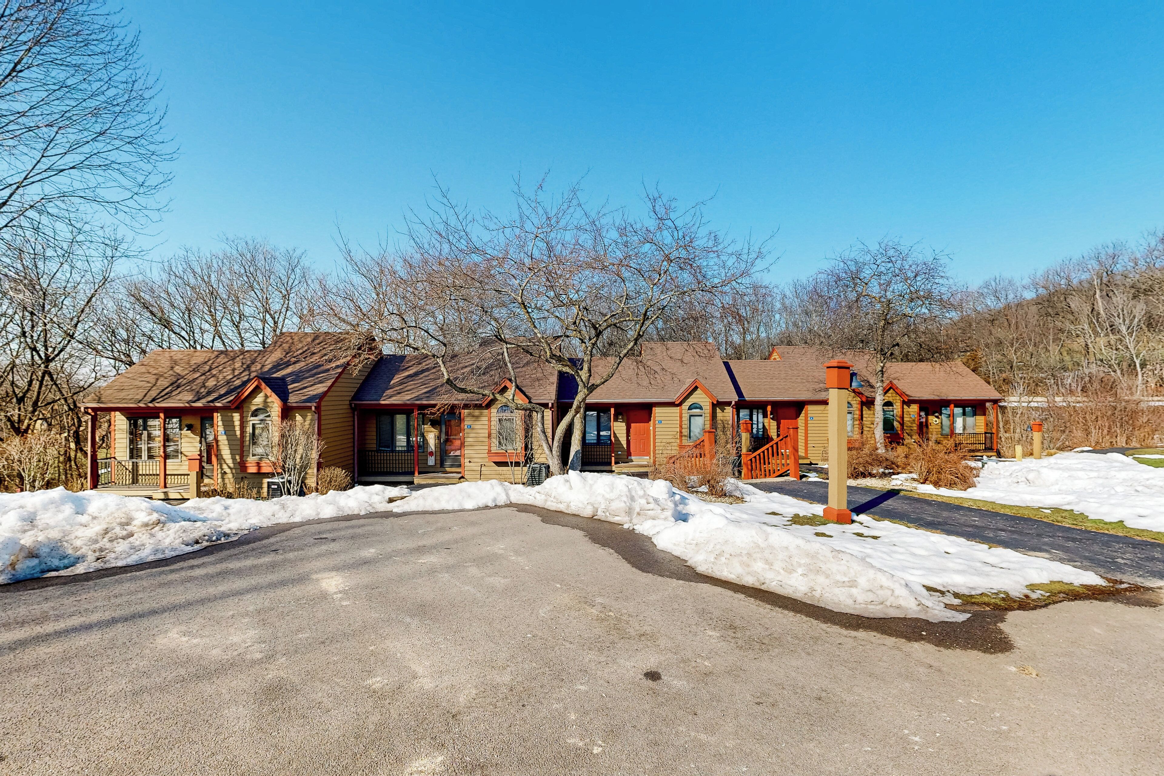 Une rangée de chalets en bois aux toits inclinés, une allée pavée et de la neige au sol.