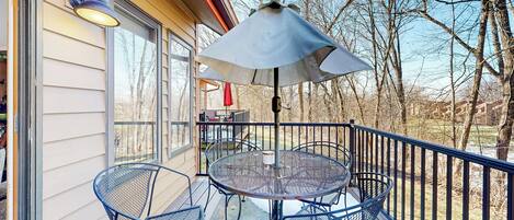 Een metalen tafel en stoelen op een balkon, met een metalen parasol.