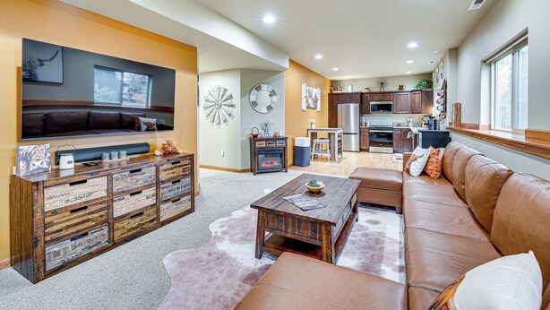 A spacious living room with a large brown leather sofa, a wooden coffee table, and a TV mounted on a wooden cabinet. - Near Ferry, Shops & Eats! Anacortes Townhome (Anacortes)