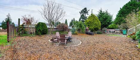 A patio area with a table and chairs, surrounded by a wooden fence and various trees.