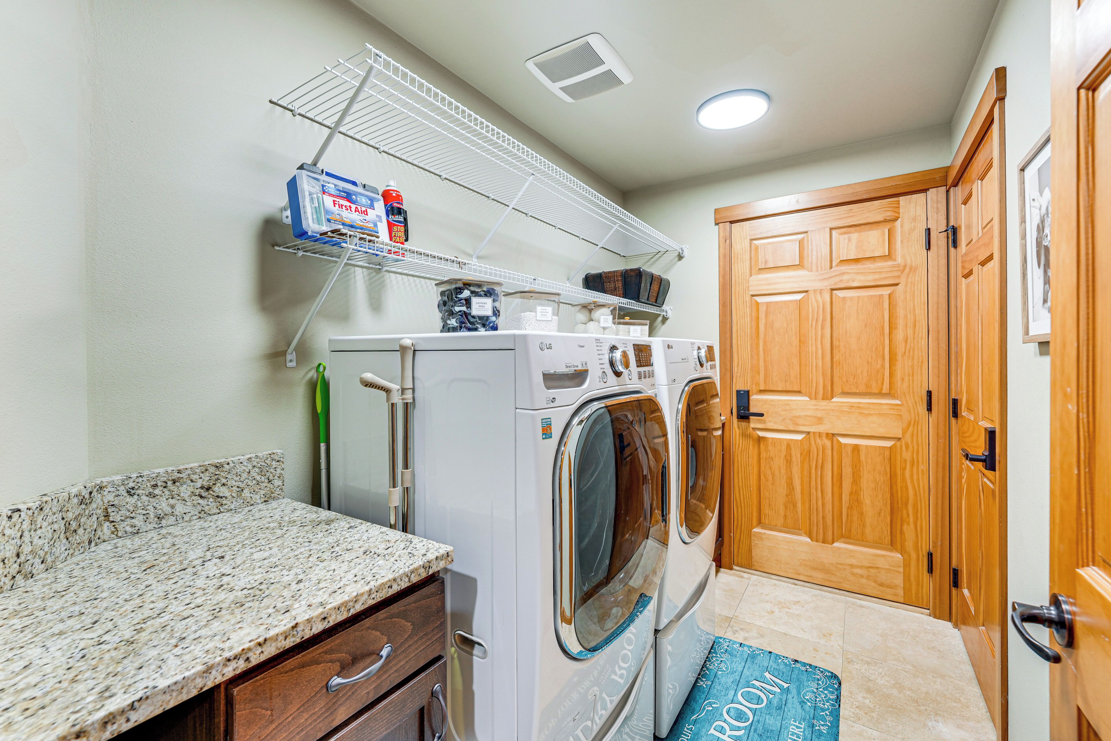 A laundry room with a washing machine, dryer, and a shelf with laundry supplies.