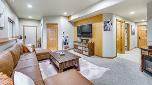 A spacious living room with a brown leather sofa, a wooden coffee table, and a flat-screen TV mounted on the wall. - Near Ferry, Shops & Eats! Anacortes Townhome (Anacortes)
