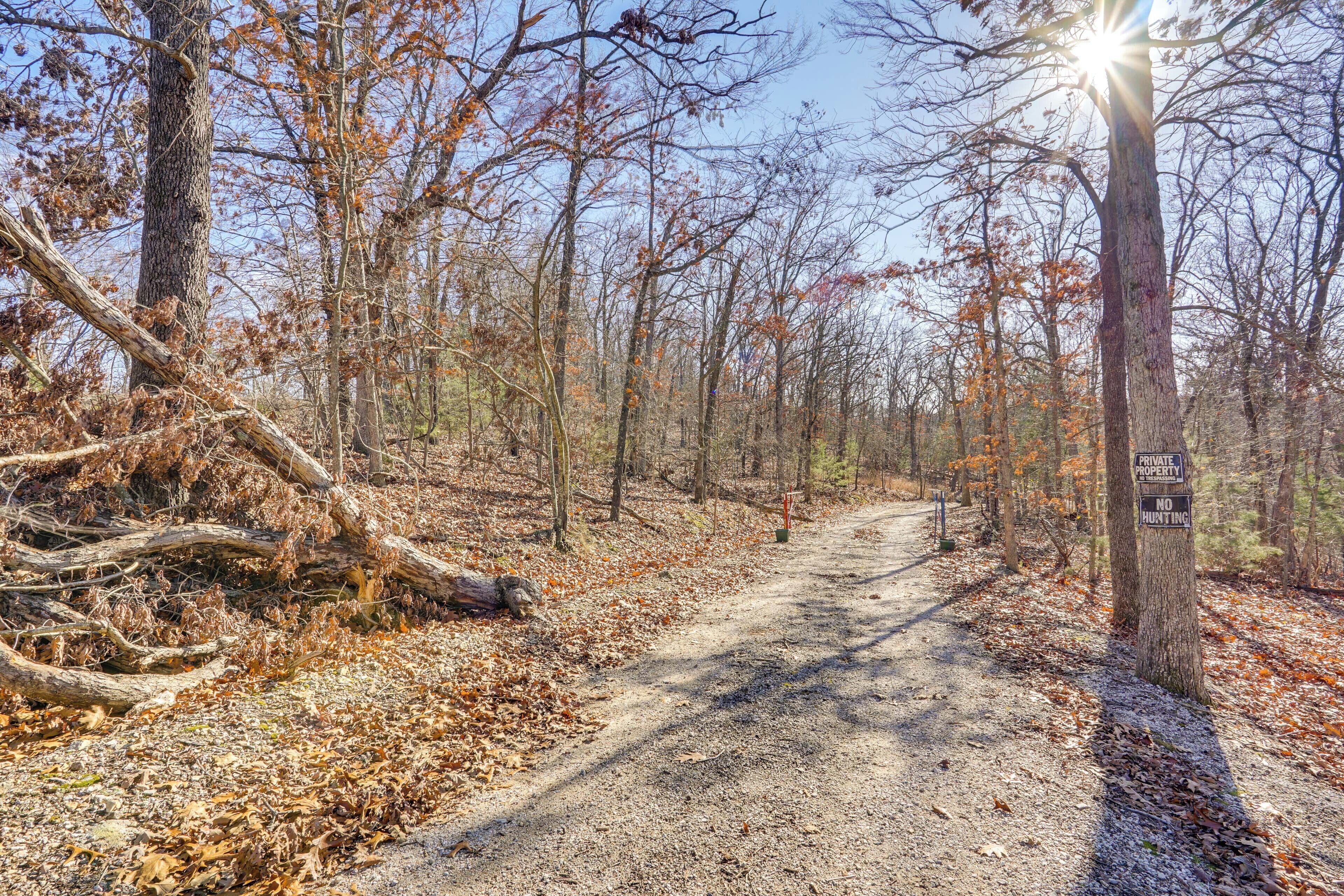 A forested path with a sign indicating it is private property and no hunting allowed.