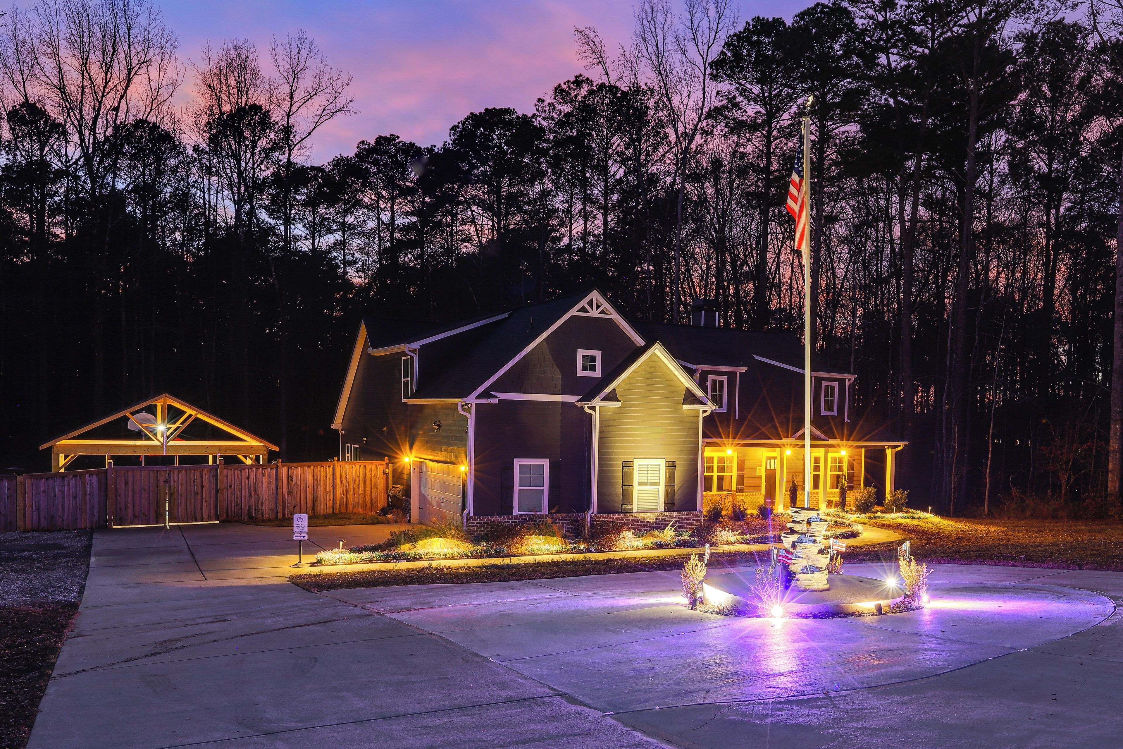 A residential house with a well-lit driveway and a small garden area.