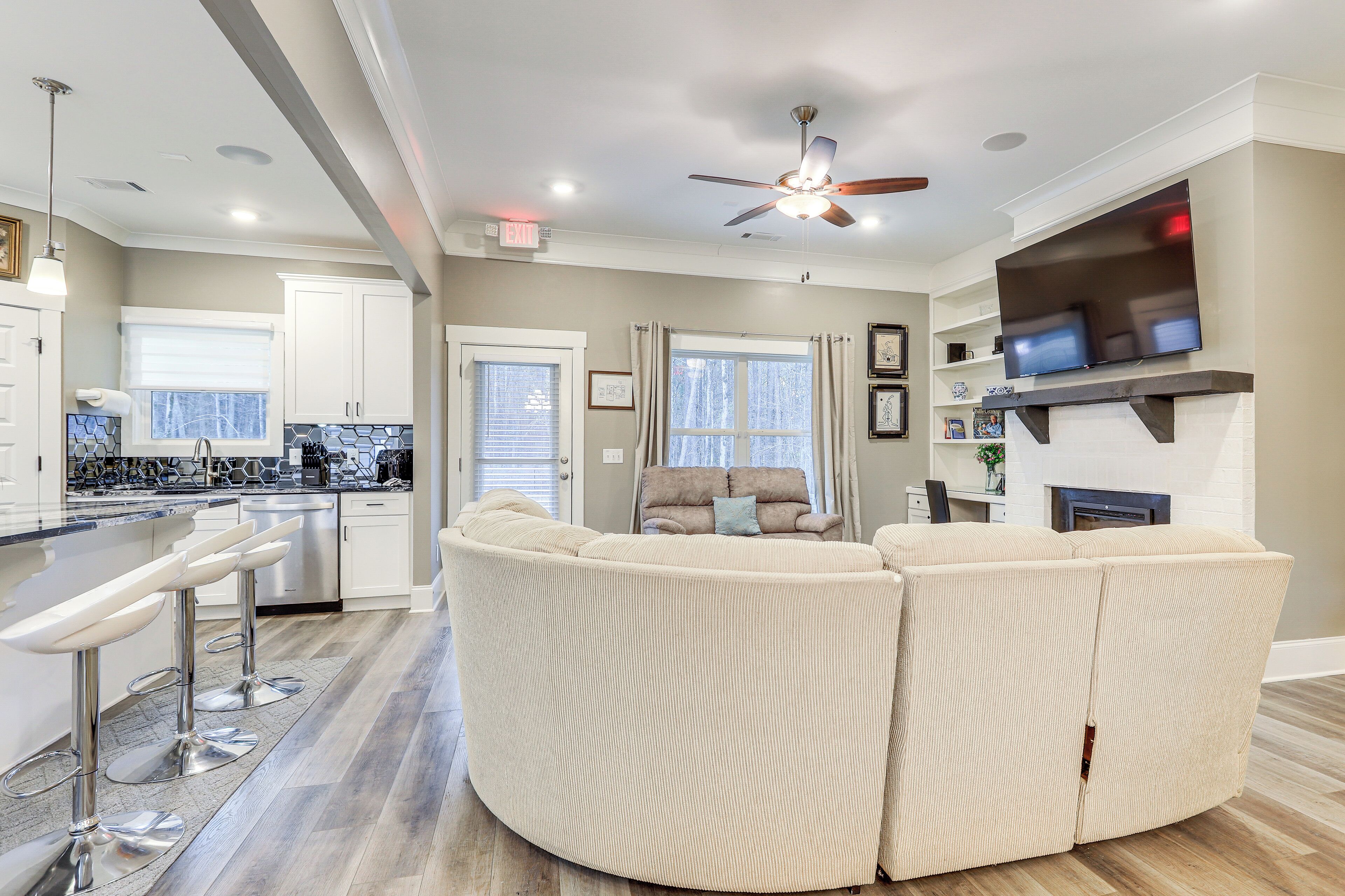A modern kitchen with white cabinets, a bar area, and a ceiling fan.