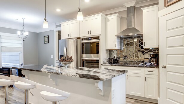 A modern kitchen with white cabinetry, stainless steel appliances, a marble island with bar stools, and pendant lighting. - Gather, Play & Unwind! Modern Locust Grove Home (Locust Grove)