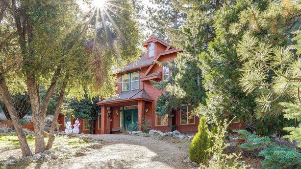 A two-story house with a red exterior, surrounded by trees and a gravel driveway. - Games Galore! Pine Mountain Club Retreat Near Town (Pine Mountain Club)