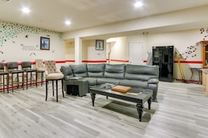 A living room with a leather sofa, a coffee table, and bar stools. - Clarksburg Getaway Near DC + Baltimore Sights! (Clarksburg)