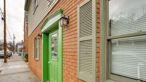 A brick building with a green door and shutters, a visible window, and a sidewalk. - Walk to Shops & Eats: Apt in Downtown Elizabeth (Elizabeth)