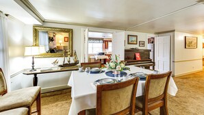 A dining room with a white table set for four, a piano, and a mirror on the wall. - Walk to Shops & Eats: Apt in Downtown Elizabeth (Elizabeth)