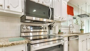 A modern kitchen with stainless steel appliances, white cabinetry, and a granite countertop. - Sand Volleyball Court, Pool, Hot Tub! Fun Retreat (Port Wentworth)