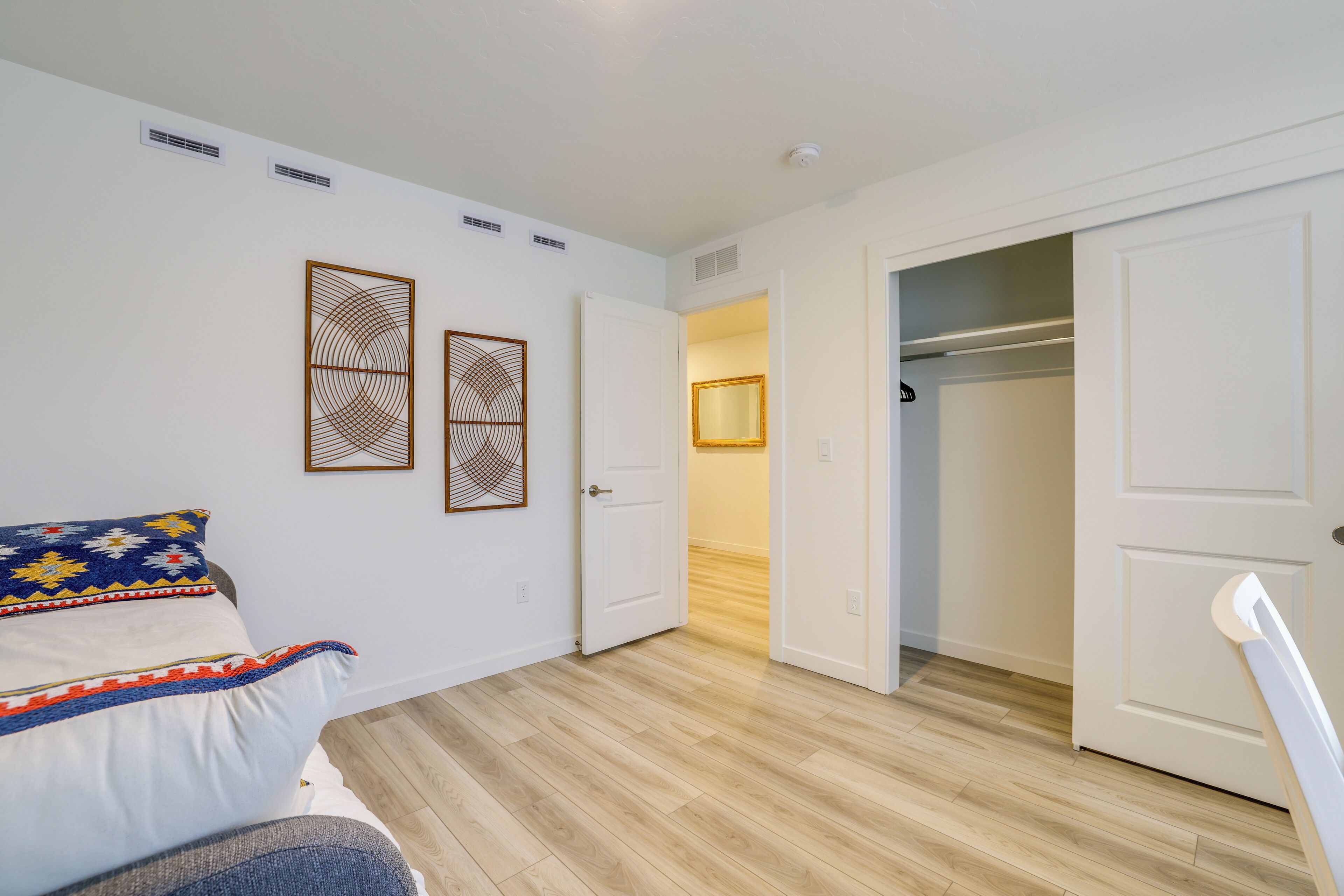 A bedroom with a bed, a wardrobe, and a hallway leading to a bathroom.