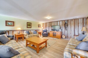 A living room with a wooden coffee table, two sofas, a TV, and a wooden cabinet. - 100-acre Family Getaway in Kenbridge: Pets Welcome (Kenbridge)