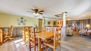 A spacious living area with a wooden dining table and chairs, a kitchen area with a TV, and a cozy seating area with a plaid sofa. - 100-acre Family Getaway in Kenbridge: Pets Welcome (Kenbridge)