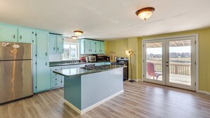A modern kitchen with light blue cabinets, a stainless steel refrigerator, and a large island. - 100-acre Family Getaway in Kenbridge: Pets Welcome (Kenbridge)