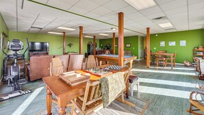 A spacious room with green walls, wooden furniture, a pool table, and exercise equipment. - 100-acre Family Getaway in Kenbridge: Pets Welcome (Kenbridge)