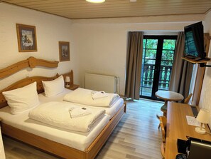 A hotel room with a wooden bed, a desk, a chair, a TV, and a window with curtains. - Gästehaus Tönisvorst (Toenisvorst)