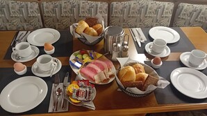 A dining table set with plates, cutlery, bread, eggs, and condiments.
