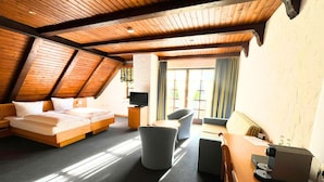 A room with a loft bed, a sofa, a dining table, and a coffee machine.