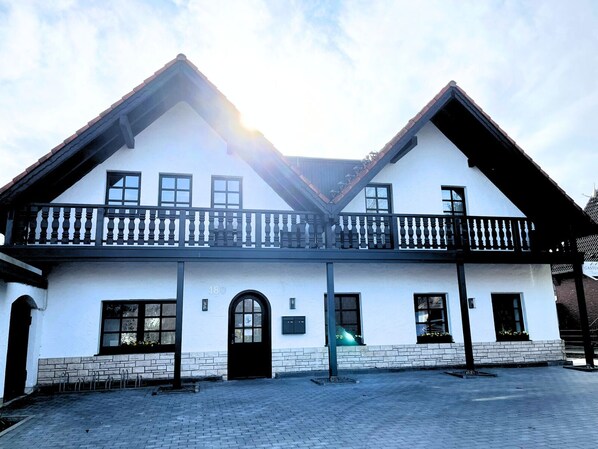 A two-story building with a balcony, a brick foundation, and a number '180' on the wall. - Gästehaus Tönisvorst (Toenisvorst)