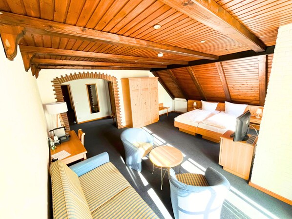 Acogedor dormitorio en el ático con cama, zona de estar y escritorio.