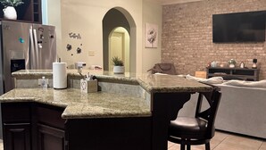 A kitchen with a central island, dark cabinetry, granite countertops, and a ceiling fan.
