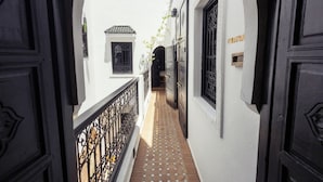A narrow alleyway with white buildings, black doors, and a tiled floor. - Hotel with 5 bedrooms and AC in charming Marrakesh 
your cozy stay book it now (Marrakesh)