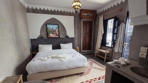 A bedroom with a large bed, a wooden door, a small table, and a nightstand. - Hotel with 5 bedrooms and AC in charming Marrakesh 
your cozy stay book it now (Marrakesh)
