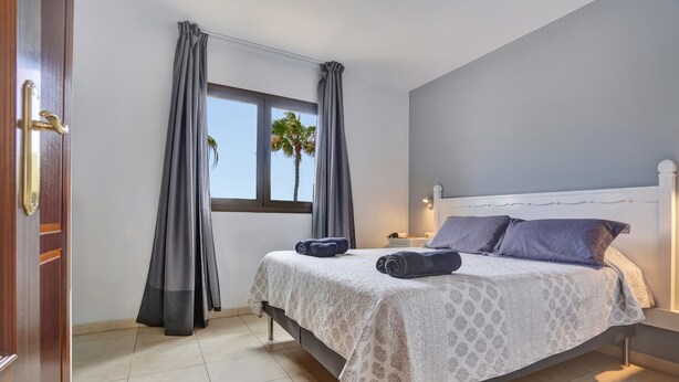 Un dormitorio con cama, cortinas, ventana y puerta.