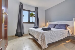 A bedroom with a bed, curtains, a window, and a door. - Vacation Apartment 'Oasis Royal F306' with Shared Pool, Private Terrace and Wi-Fi (Corralejo)
