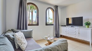 Una sala de estar moderna con un sofá, una mesa de centro de vidrio, un televisor y un mueble aparador.