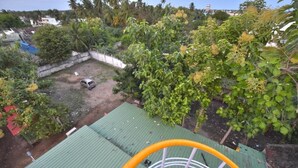A rooftop with a green metal roof, a white railing, and a small vehicle parked in the background.
