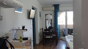 Een kamer met een bed, een bureau, een stoel, een televisie en een raam met gordijnen.