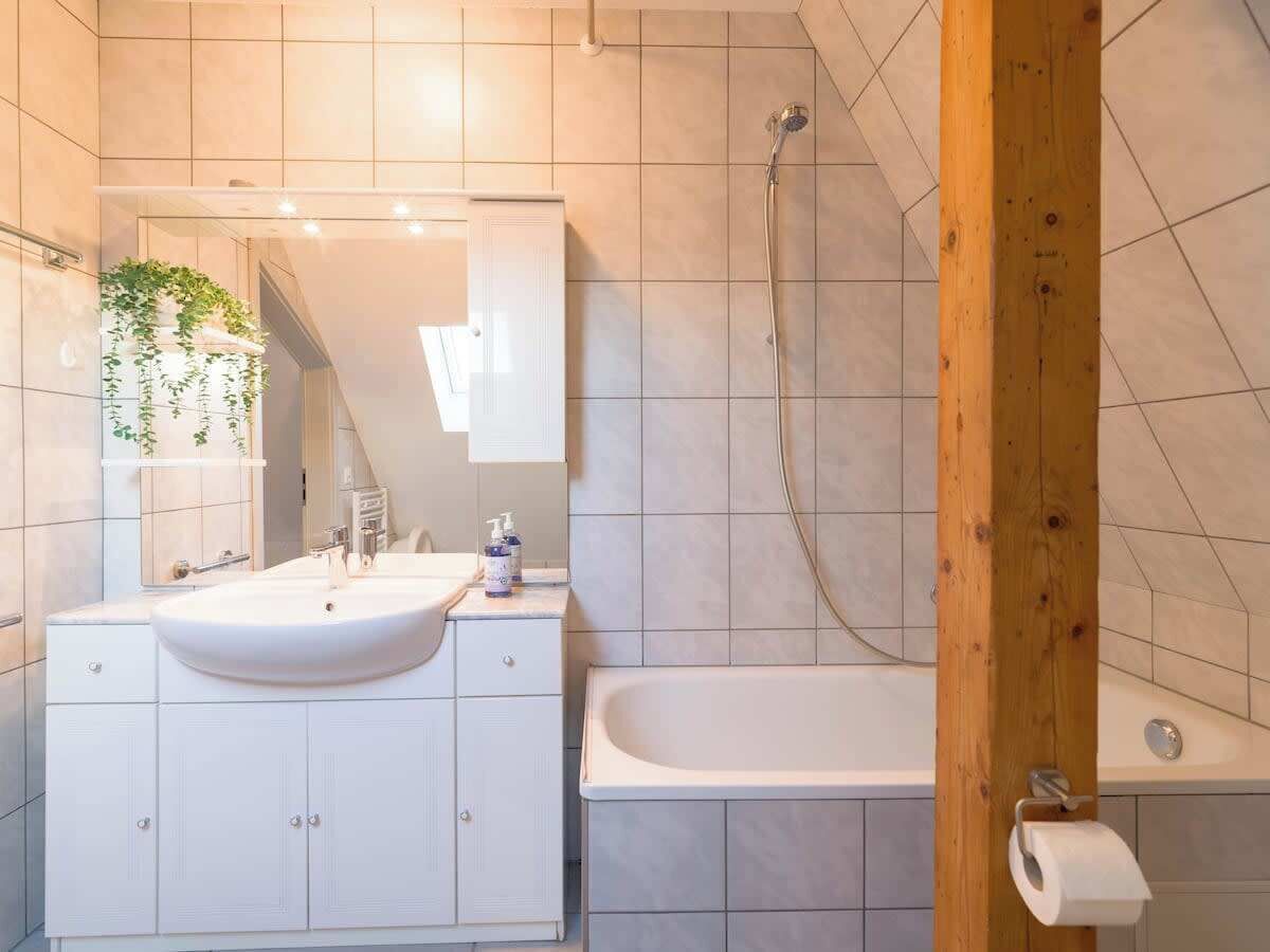 Une salle de bain moderne avec un meuble-lavabo blanc, un grand miroir, un évier, une baignoire et une douche.
