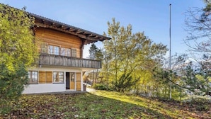 A wooden chalet with a balcony, surrounded by trees and a clear sky. - Alpine Garden Retreat | Panoramic Mountain Views (Reichenbach im Kandertal)