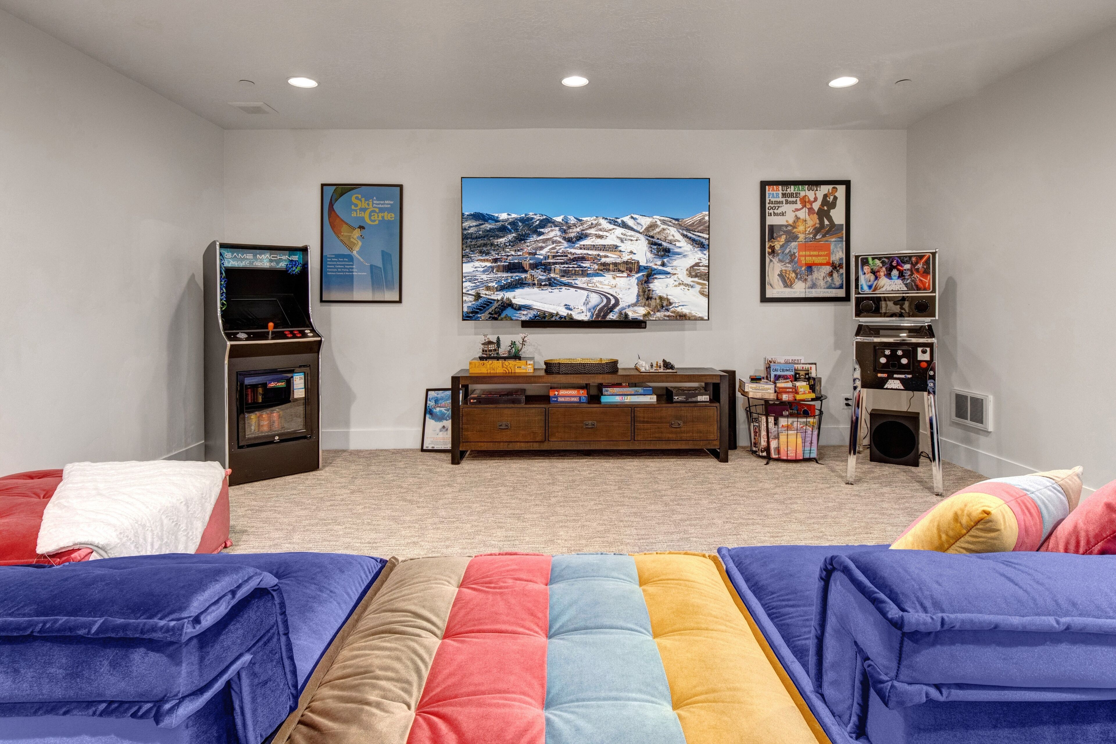 A cozy room with a large TV, a bookshelf, and a comfortable couch.