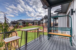 A wooden deck with a bench and chairs, overlooking a well-maintained lawn and neighboring houses. - Frost Haven 4 Bedroom Townhouse (Park City)
